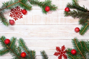 Noel arkaplanı - köknar dalları ve beyaz ahşap bir masada kırmızı süslemeler. Düz düzen, kopyalama alanı ile üst görünüm bileşimi sınırı.