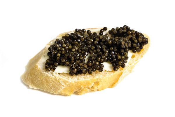 Baguette slice with black caviar and butter isolated over white. Natural sturgeon luxury delicacy sandwich closeup. Seafood delicatessen and bread appetizer.