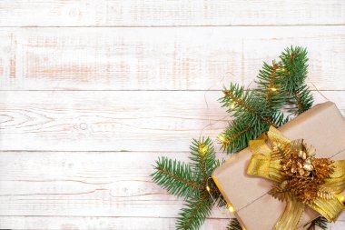 Noel arkaplanı - köknar dalları, hediye kutusu ve beyaz ahşap bir masanın üzerindeki ışık çelengi. Düz düzen, kopyalama alanı ile üst görünüm bileşimi sınırı.