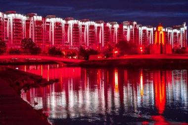 Minsk, Belarus 'un tarihi merkezinin gece manzarası. Nehrin üzerinde kırmızı ışık köprüsü.