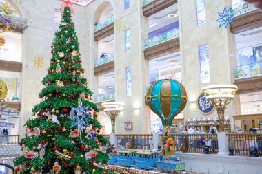 Moscow, Russia - December 07, 2016: Christmas tree with decorations in a Central Children's Store shopping mall. Walking people on background. New Year, winter holidays, gifts buying. clipart