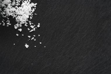 Siyah taş zemin üzerinde organik deniz tuzu. Doğal sağlıklı yemek pişirme kavramı. Boşluğu kopyala. 