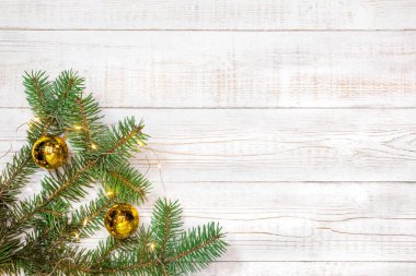 Noel arkaplanı - altın madalyalı köknar dalları ve beyaz ahşap bir masanın üzerinde hafif bir çelenk. Düz düzen, kopyalama alanı ile üst görünüm bileşimi sınırı.