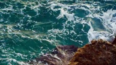 Güzel doğal deniz dalgaları. Turkuaz su kayanın üzerine sıçrıyor, yavaş dalgalar. Sakinleştirici doğa sahnesi.