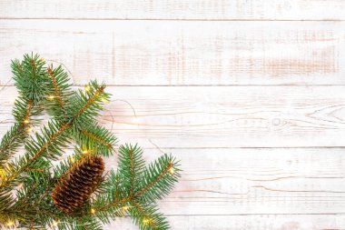 Noel arkaplanı - beyaz ahşap bir masanın üzerinde hafif çelenkli köknar dalları. Düz düzen, kopyalama alanı ile üst görünüm bileşimi sınırı.