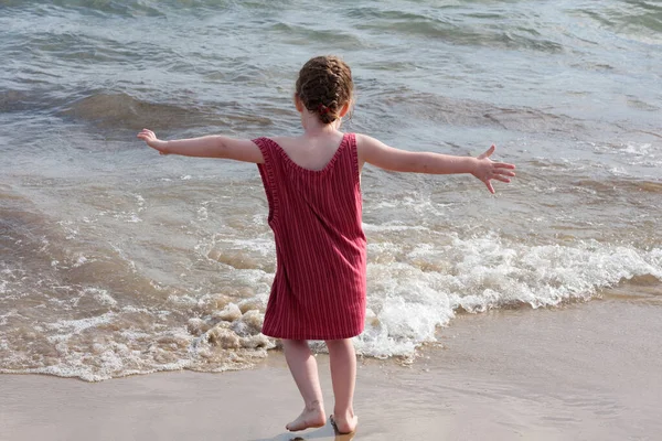Μικρό Κορίτσι Στην Παραλία Ένα Κόκκινο Φόρεμα Χέρια Απλωμένα — Φωτογραφία Αρχείου