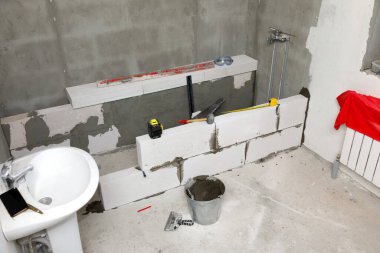 Beton blokları ve inşaat aletleri olan yeni bir banyonun içi..