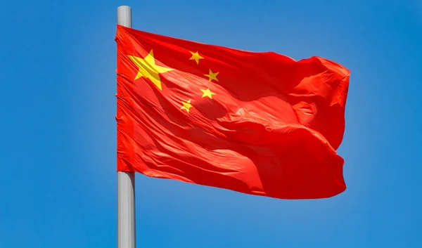 Flag of China waving in the wind against the blue sky background.