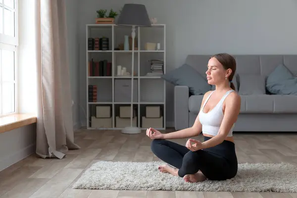 Evde Yoga Yapan Lotus Pozisyonunda Oturan Genç Bir Kadın - Stok İmaj