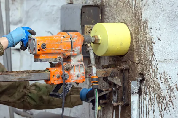コンクリートの壁に穴を作るために電気ドリルを使用して労働者 ロイヤリティフリーのストック画像
