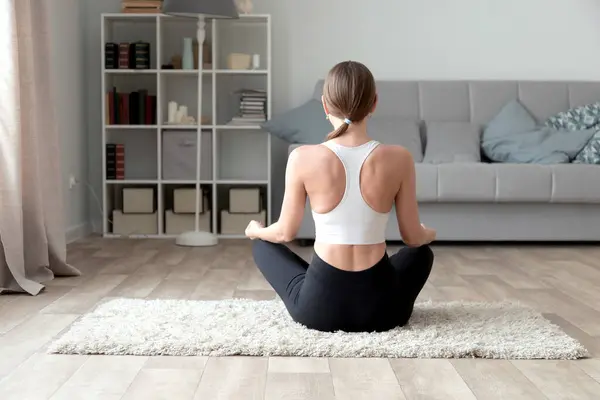 Junge Frau Praktiziert Yoga Hause lizenzfreie Stockfotos