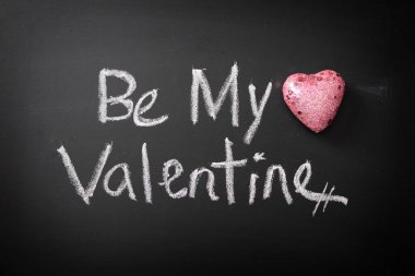 Be My Valentine written in chalk on blackboard with glittery pink heart