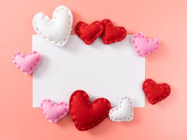 Blank valentine card on pink background with red. pink, and white sewn hearts surrounding