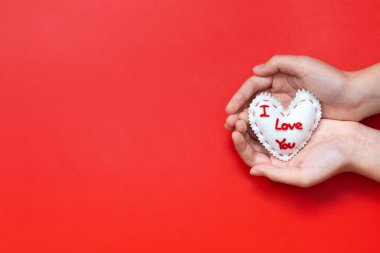 I Love You sewn valentines heart cupped in hands on red background
