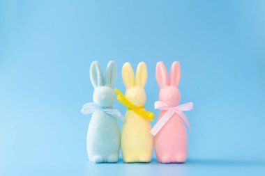 Pastel colored easter bunny decorations lined up on blue background