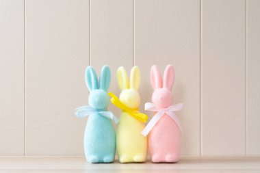 Pastel colored easter bunny decorations lined up on white background