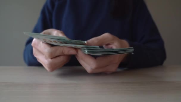 女性手在桌上清点堆积如山的100美元钞票的特写镜头 视频剪辑