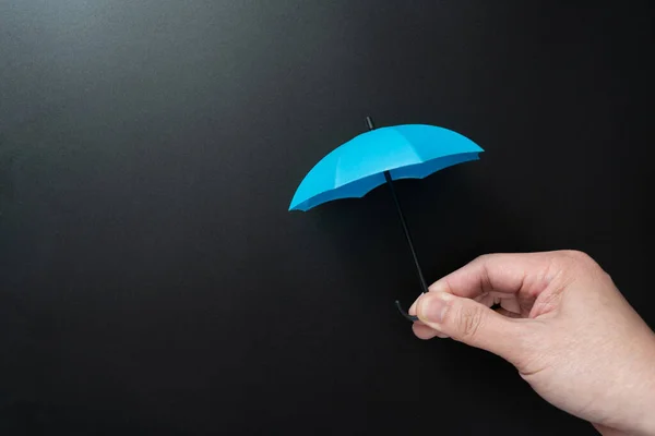 手持迷你开的蓝色伞 与空白黑色背景隔离 免版税图库图片