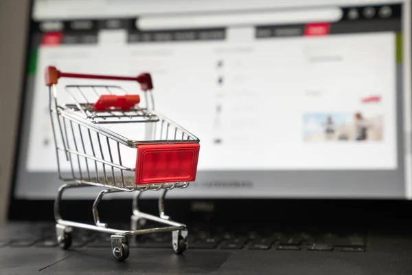 Laptop with a small red shopping cart for e-commerce or online shopping concept.