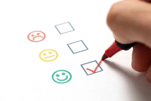 Happy customer checked mark tick on the smiley face icon on product quality and customer satisfaction survey and questionnaire checklist sheet with a red pen