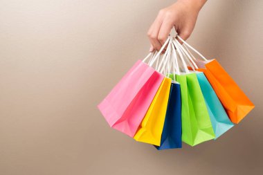 Çok renkli hediyeler ya da satış ve fiyat pazarlığı etkinliği için kahverengi arka planda izole edilmiş alışveriş çantaları..