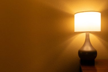 Masadaki parlak masa lambası turuncu duvar arka planında izole edilmiş, minimalist tasarım.