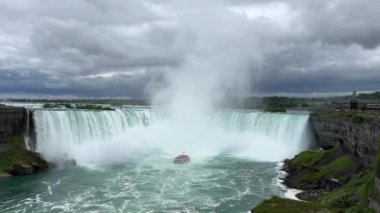 Kırmızı pançolu turistlerle dolu bir tur teknesi Niagara Şelalesi 'ndeki Horseshoe Şelalesi' nin tabanında sise doğru yol alıyor..