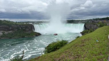 Kırmızı pançolu turistlerle dolu bir tur teknesi Niagara Şelalesi 'ndeki Horseshoe Şelalesi' nin tabanında sise doğru yol alıyor..