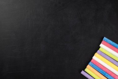 Eğitici veya yaratıcı tasarımlar için kullanılan çok renkli tebeşirlerle biraz pürüzlü siyah ya da koyu renk duvar dokusu yüzeyi