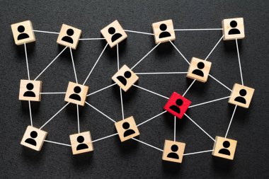 Tahta blok küpleri siyah arka planda kırmızı bir küp simgesiyle birbirine bağlanmış. Bir organizasyonda liderlik, seçkin ve takım çalışması konsepti.