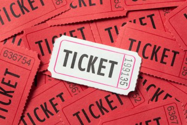 Film teması tasarımı için bir sürü kırmızı koçanlı biletin üstüne tek beyaz klasik giriş bileti.