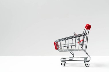 yan closeup parlak alüminyum boş minyatür beyaz arka plan üzerinde izole kırmızı saplı süpermarket sepeti göster