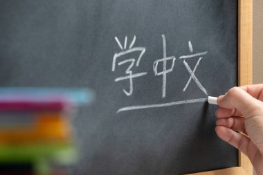 Çince dersinde, üstünde Çince öğrenme kelimesi yazan bir tahtaya el yazısı. Bazı kitaplar ve okul malzemeleri..