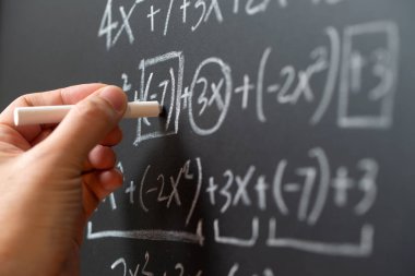 Matematiksel işlemler ve matematik formülü tahtaya tebeşirle yazılmış.
