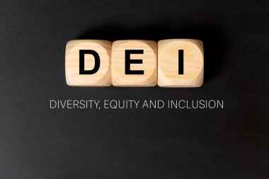DEI harfleri siyah arkaplanda üç tahta küp üzerine yazılmış, yani çeşitlilik, özsermaye ve kapsama.