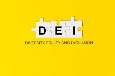 DEI harfleri üç parça yapboz üzerine yazılmış sarı arka plan, çeşitlilik, özsermaye ve kapsama anlamına gelir.