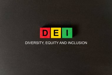 Siyah arkaplanda kırmızı, sarı ve yeşil küplerle ilgili DEI kelimeleri, yani çeşitlilik, özsermaye ve kapsama.