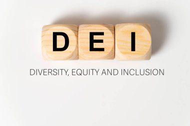 DEI harfleri beyaz zemin üzerinde üç tahta küp üzerine yazılmış, bu da çeşitlilik, özsermaye ve kapsama anlamına gelir.