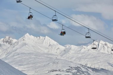 LA PLAGNE, FRANCE - CIRCA 2016: Dağların üzerinden güzel manzaralı bir yamaçta parlak güneş ışığında kayak kaldıranlar ve kayakçılar. Paradiski kayak merkezinin bir kısmı, Avrupa 'nın en büyüklerinden biri.