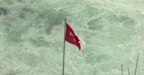 瑞士国旗在莱茵河瀑布快速流淌的河水中挥动 — 图库视频影像