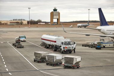 Havaalanındaki bir tank kamyonu bir jet uçağına yakıt ikmali yapıyor, uçak yakıt ikmali yapıyor.