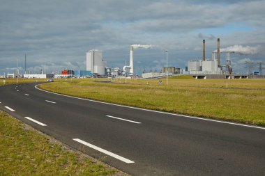 Smoking power plant chimney in an industrial area, and other industrial facilities in the port of Rotterdam