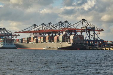 Cranes of a container shipping terminal in the port of Rotterdam, huge cargo ship loading