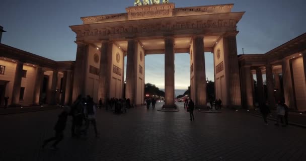 ベルリン ドイツ Circa 2022 ベルリンの中心部にある歴史的なランドマークであるブランデンブルク門を歩く 夜の光が差し込む深夜の青時間帯の観光客 — ストック動画