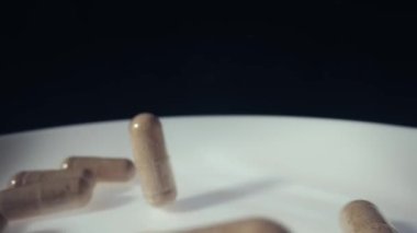 İlaç hapları, kapsüller 120 fp 'den yavaş çekimde bir tabağa düşüyor.