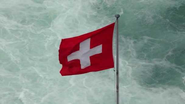 瑞士国旗在瑞士莱茵河瀑布快速流淌的山水中飘扬 — 图库视频影像