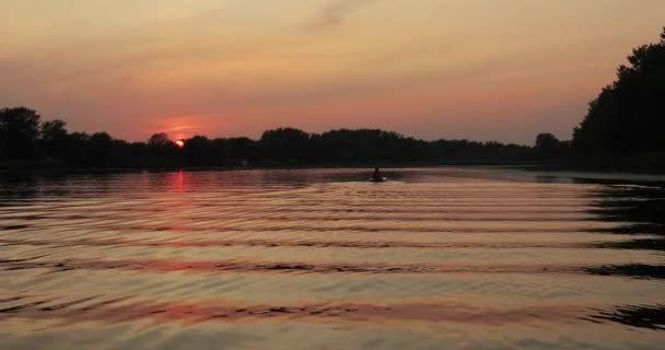 美しい夕日の光の反射で湖の水面をリップリング 地平線上に認識できないカヤック — ストック動画