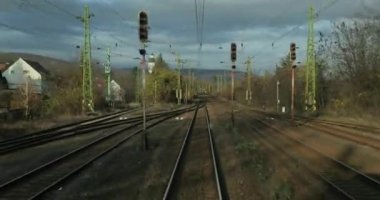 Tren yolculuğu bakış açısı arkadan, tren rayları kırsal bir istasyondan ayrılıyor.