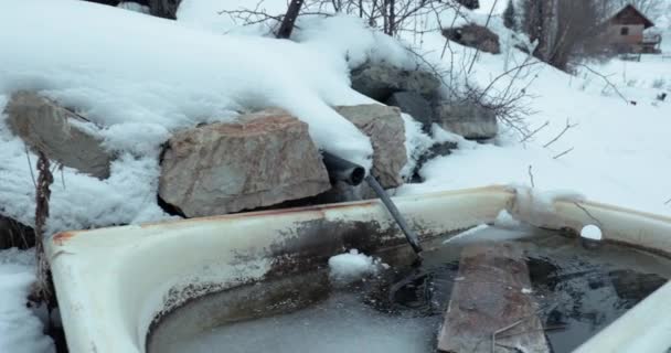 山の村のリモート風景の中に流れる冷たい春と古い浴槽 — ストック動画