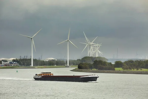 ロッテルダム港の工業用運河沿いの風力タービン 水路を通過する船 曇りの天候 — ストック写真